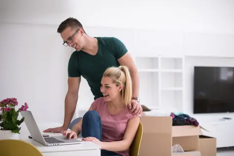 Jeune couple emménageant, compare en ligne assurance habitation, énergie, eau et internet pour installation sereine.