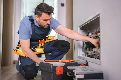 Technicien plombier réparant un système de chauffage résidentiel: diagnostic rapide, méthodes sûres, électricité et plomberie efficaces.