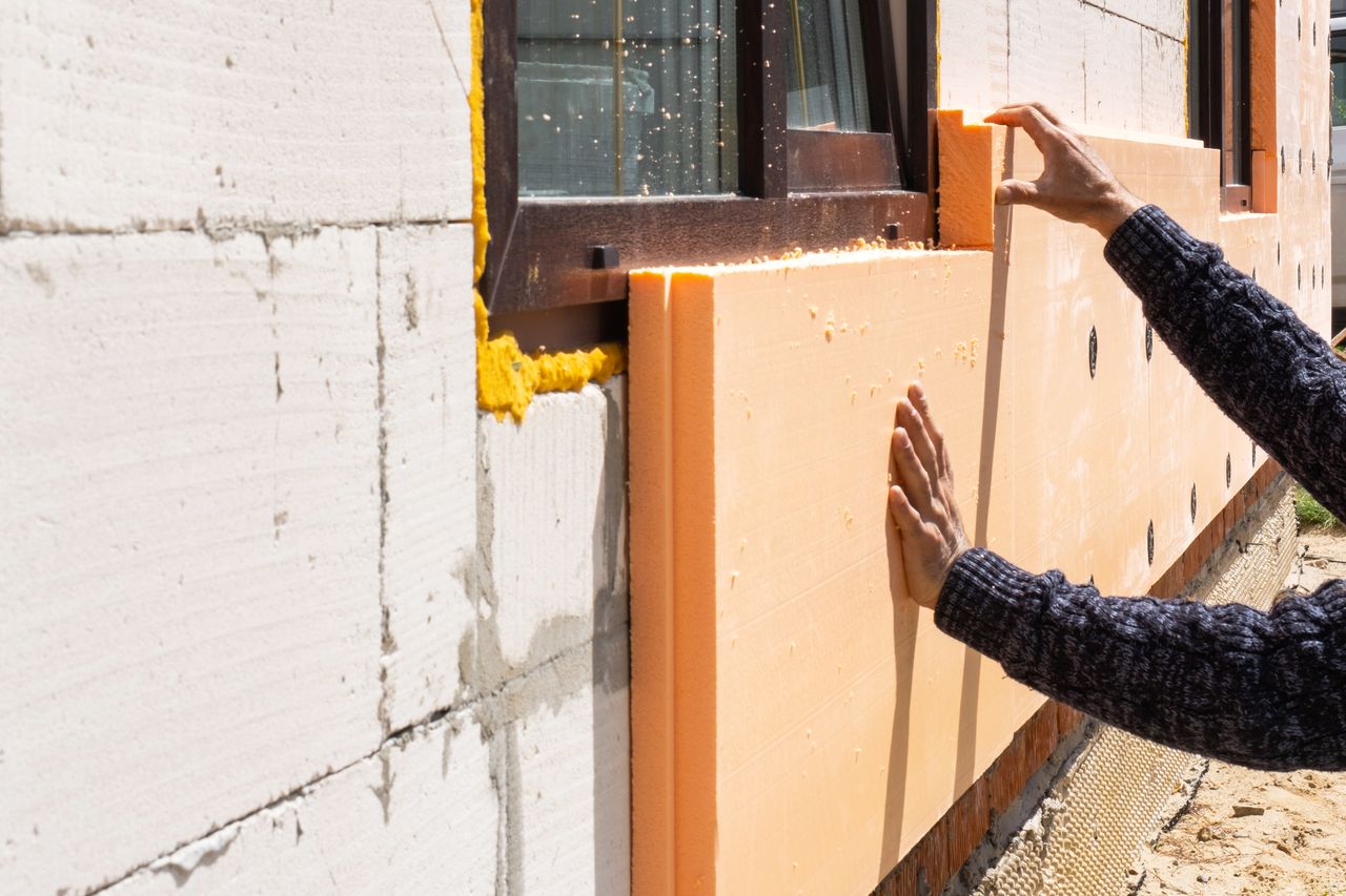 Coupe technique d’un mur intérieur isolé, panneaux d’isolants posés, mètre ruban et chantier propre.