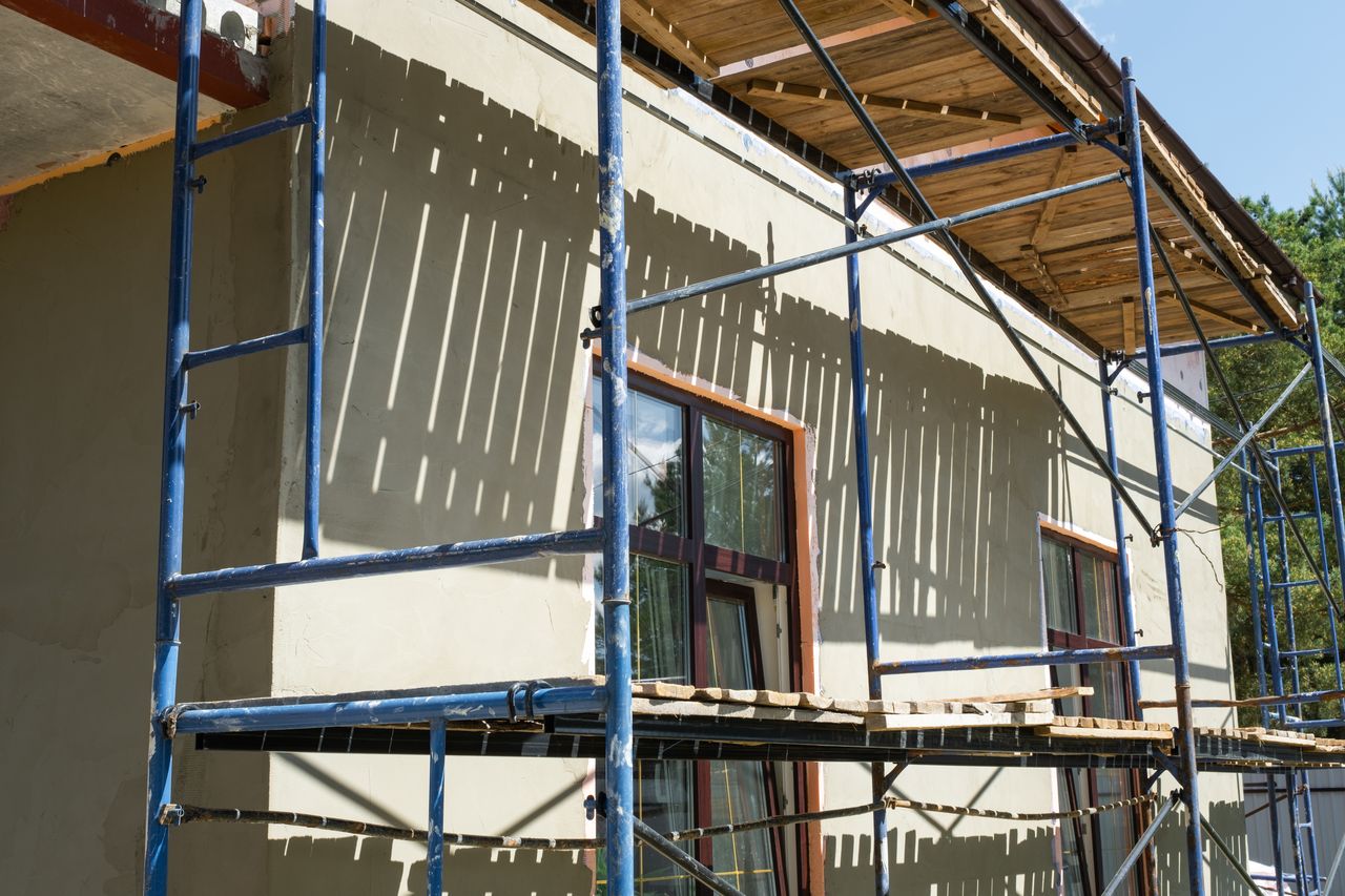 Façade de maison en rénovation avec échafaudage, enduit en cours et travaux de construction.