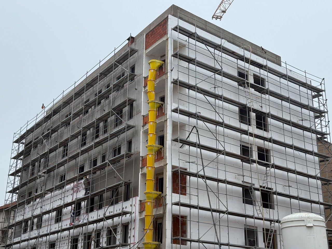 Façade d'un studio en rénovation avec isolation thermique par l'extérieur et échafaudages, améliorant le DPE sans perte de surface.