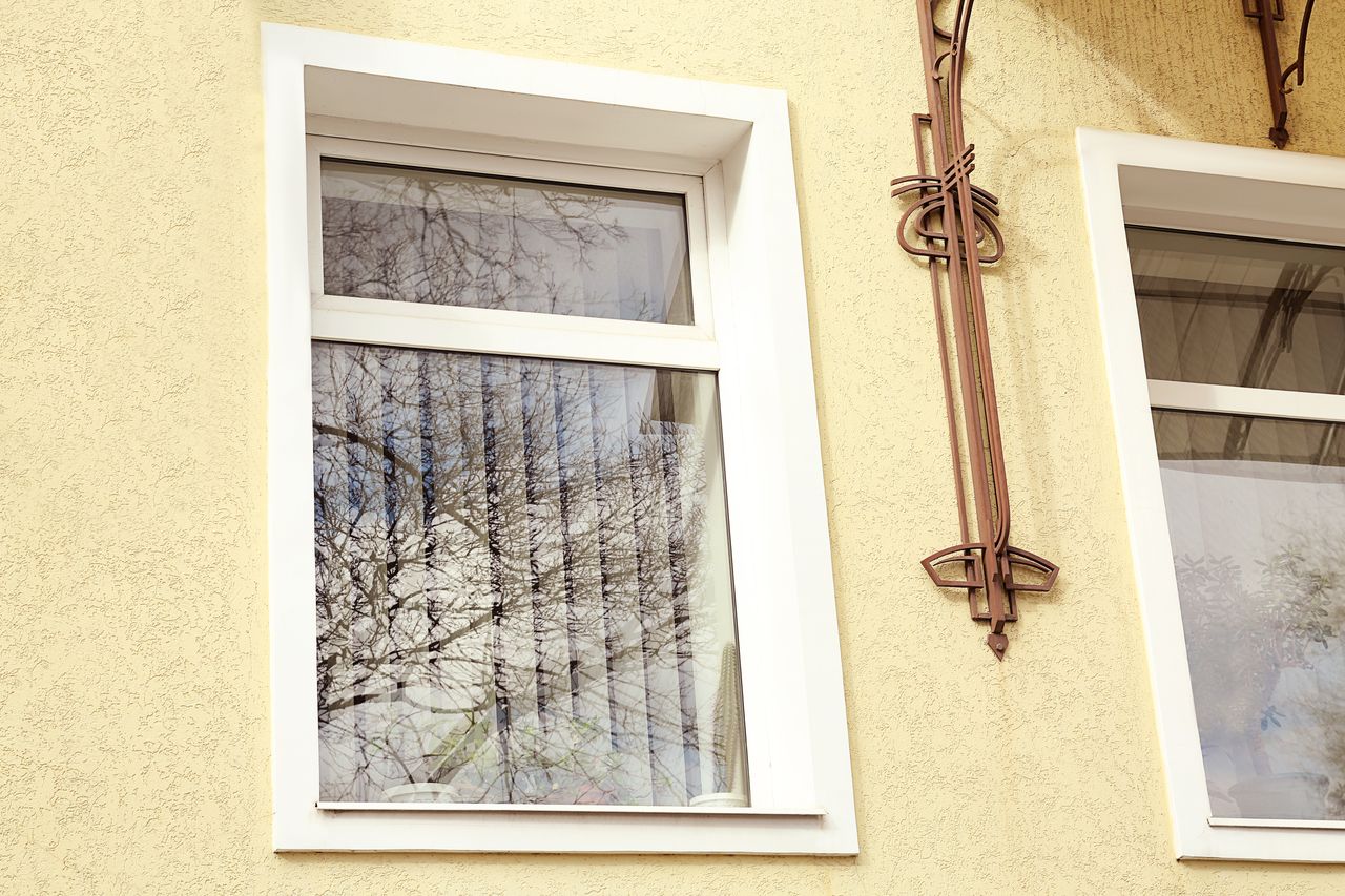 Fenêtre PVC double vitrage installée dans une façade de maison, rénovation soignée sous lumière naturelle.