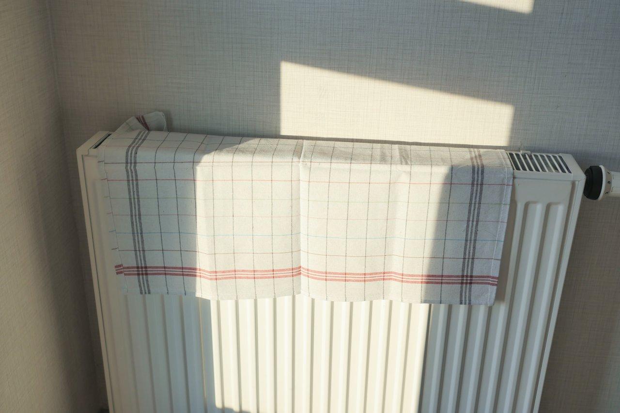 Fenêtres bien calfeutrées avec rideaux thermiques et panneau réflecteur derrière le radiateur pour une meilleure isolation thermique.