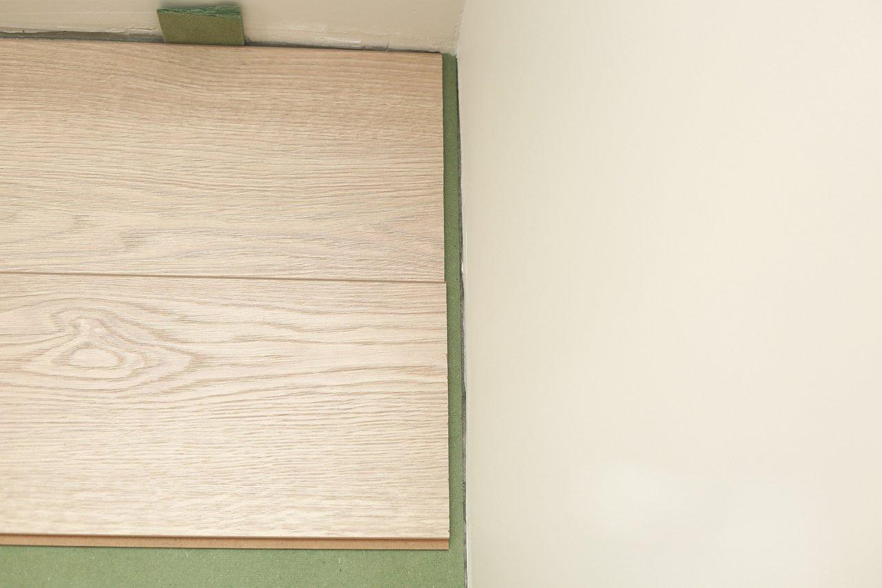 Installation de parquet stratifié flottant moderne sur carrelage ancien, étape clé pour un rendu élégant et durable.