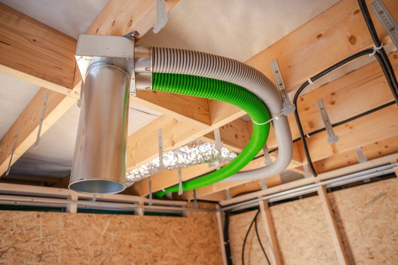 Installation d'un système de ventilation domestique dans une maison moderne en construction, avec gaines isolées dans les combles.