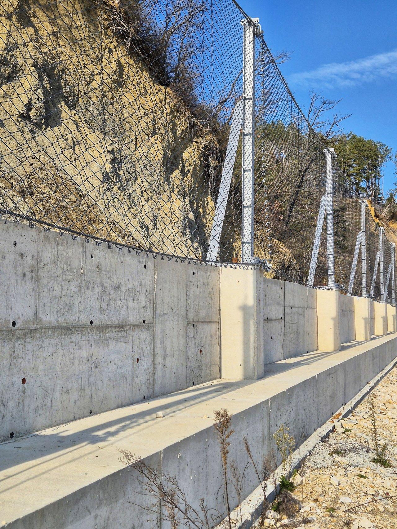 Installation d'une clôture rigide sur une pente escarpée pour assurer la stabilité et la sécurité du terrain.