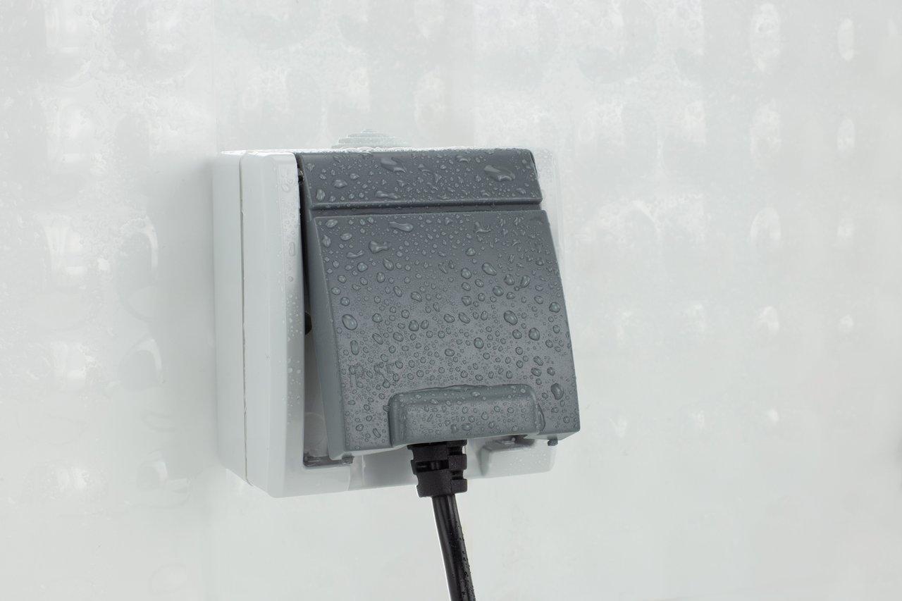 Installation d'une prise électrique extérieure étanche IP66 avec capot fermé pour une sécurité optimale en terrasse.