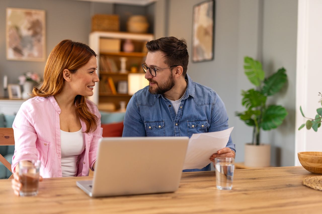 Jeune couple comparant un contrat d’assurance habitation, franchise, prime annuelle et budget à la maison.