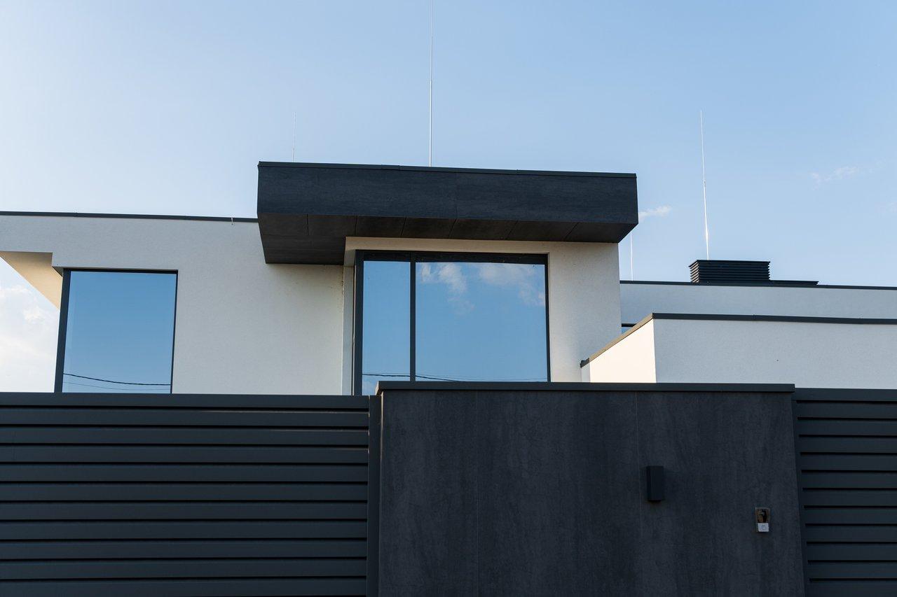 Maison moderne avec façade lumineuse, grandes fenêtres et environnement calme, idéale pour une première recherche immobilière.