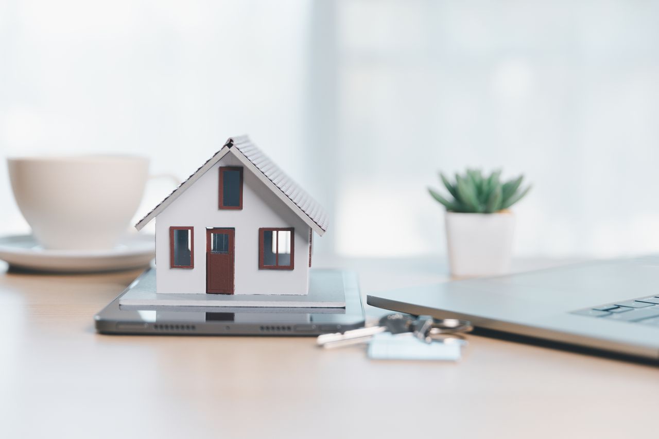 Maison neuve avec dossier de vente, calculatrice et clés sur une table pour achat immobilier.