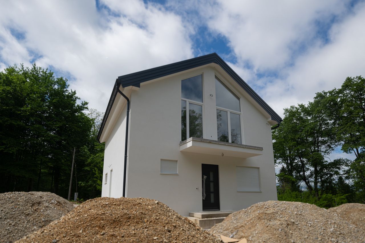Maison neuve en construction avec regard télécom, fourreau vert et technicien fibre sur chantier résidentiel.