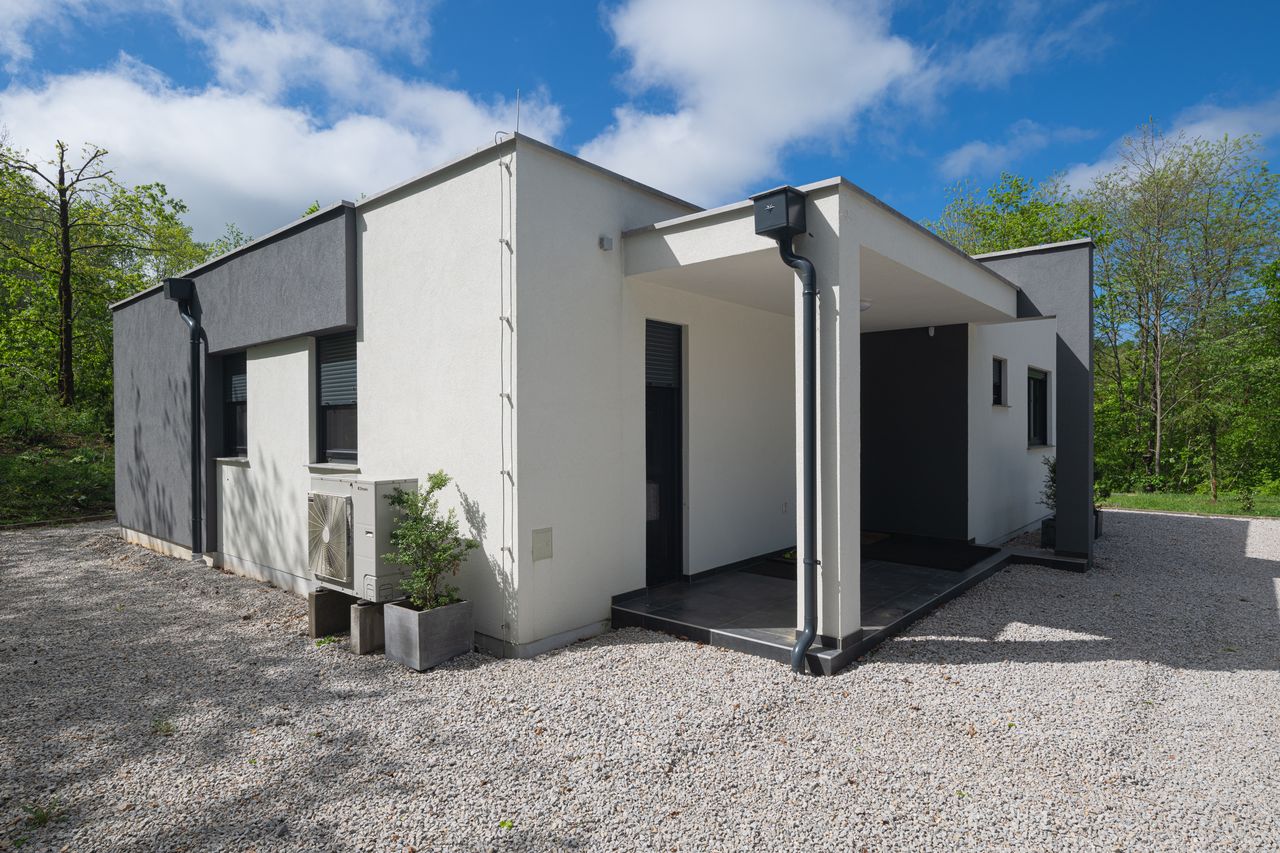 Maison passive moderne de 100 m² avec grandes baies, isolation épaisse et toiture sobre.