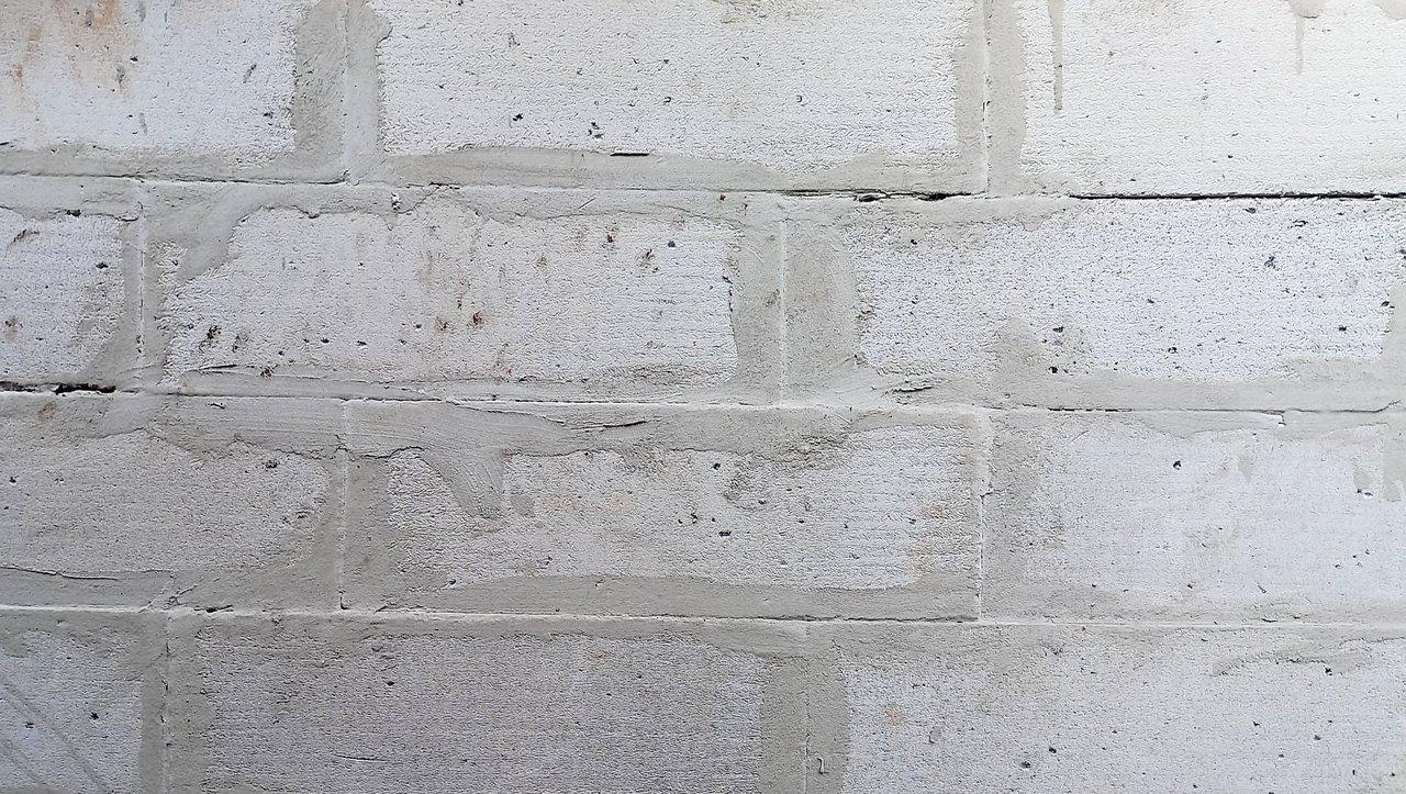 Mur en parpaing bien fini avec crépi, illustrant une construction de clôture en béton.