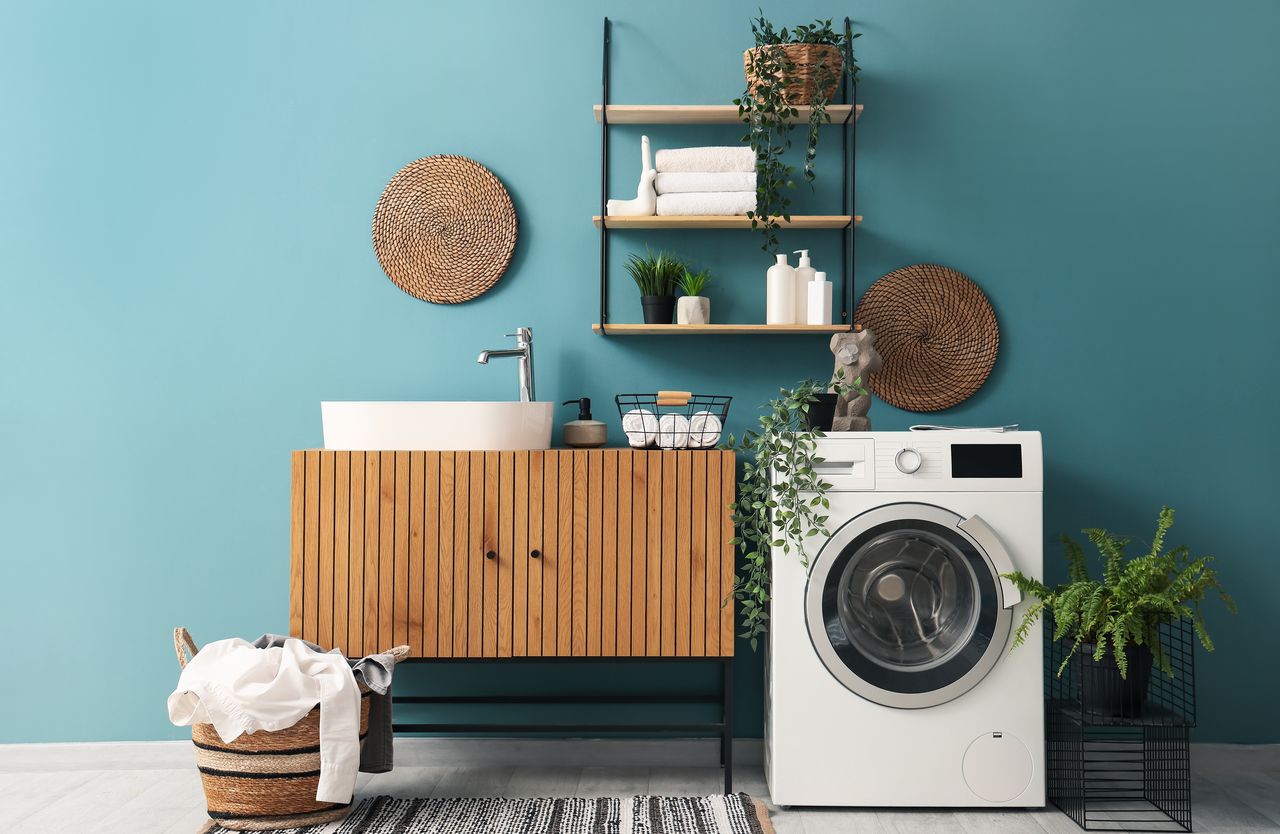Salle de bain et cuisine d’un logement récent avec lave-linge, robinet, tuyaux visibles et lumière naturelle.