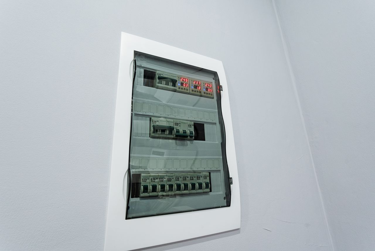 Tableau électrique domestique moderne avec disjoncteurs, prises et détecteur de fumée dans une maison récente.