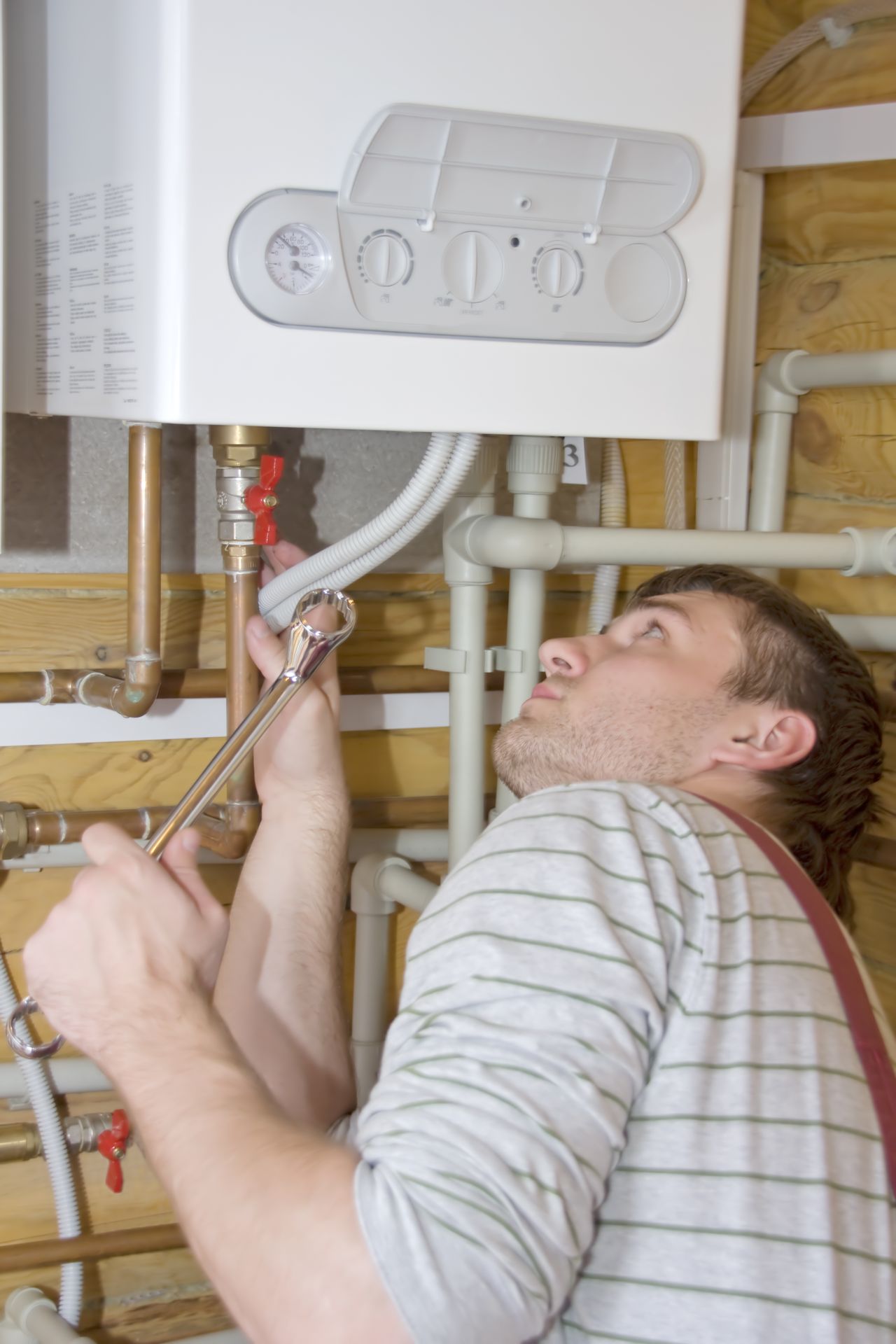 Technicien vérifiant une chaudière gaz à condensation dans une maison, pour un entretien chauffage professionnel et sécurisé