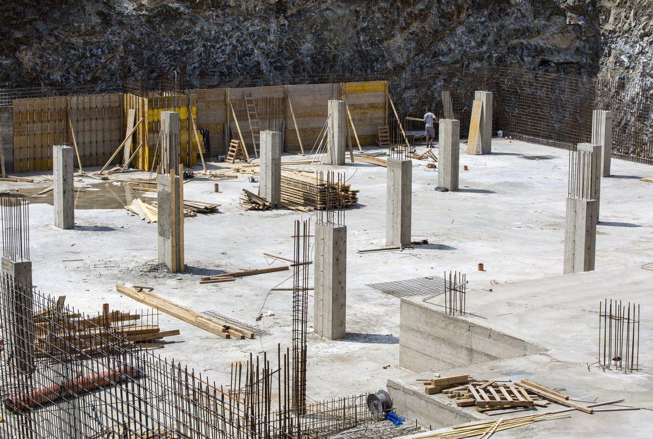 Un chantier de construction de maison en cours avec fondations, murs porteurs et équipe de professionnels sur le site.