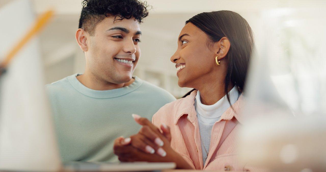 Un conseiller courtier en discussion avec un jeune couple sur un ordinateur pour choisir leur crédit immobilier.
