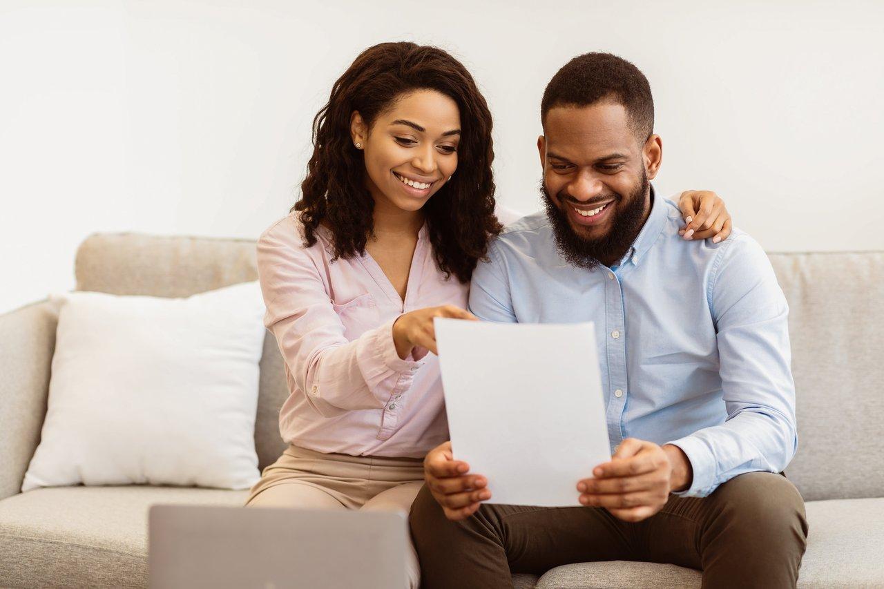 Un jeune couple étudiant les clauses d’un contrat d’assurance habitation pour leur premier achat immobilier.