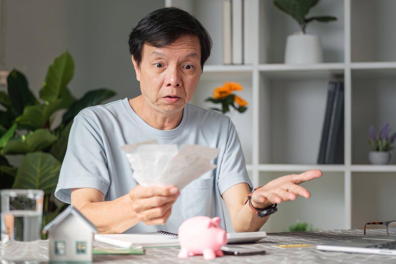 Un propriétaire consultant ses dépenses annuelles, soulignant l'importance de prévoir taxes et charges immobilières.