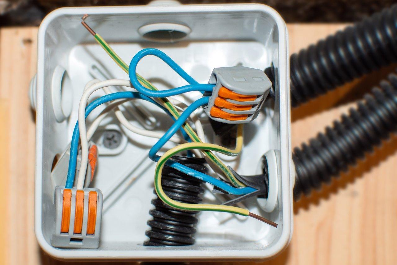 Vue rapprochée d’un boîtier d’encastrement étanche dans des combles non aménagés, garantissant une isolation sécurisée des fils électriques.